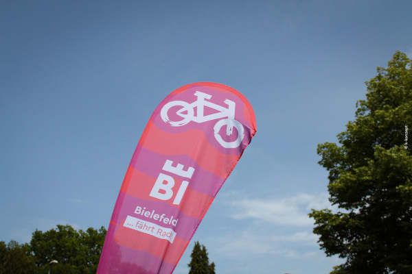 Beachflag mit der Aufschrift "Bielefeld fährt Rad" vor blauem Himmel