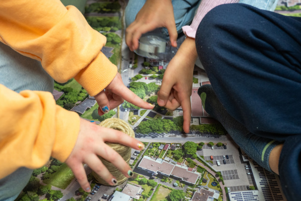 Schulkinder einer 4. Klasse orientieren sich zu ihrem Schulweg auf dem Luftbild von Baumheide. Foto: Mobildenker GmbH | ikoono